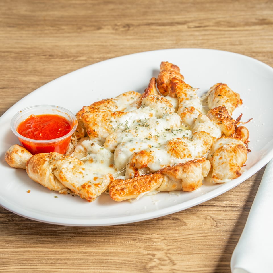 Cheesy garlic knots with herbs and a side of marinara sauce on a white plate.